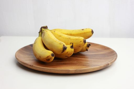 A closeup of a bunch of bananas on a brown plate isolated on a white background