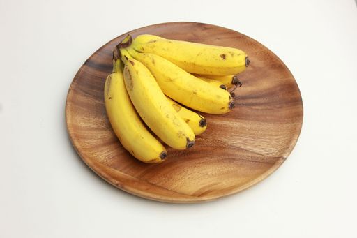 A top view of tasty bananas on a wooden plate