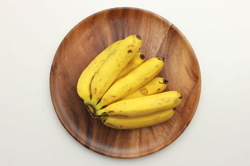 A top view of tasty bananas on a wooden plate