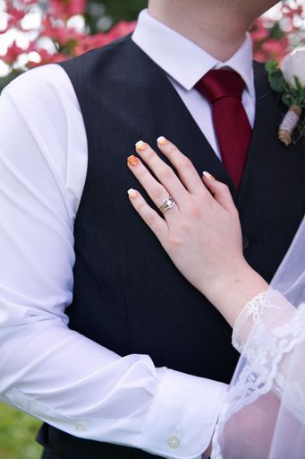 A vertical shot of a woman with a wedding ring putting her hand on the chest of the groom