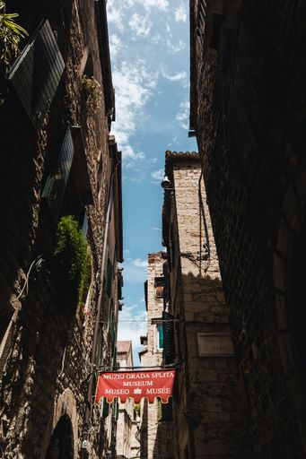 A vertical low angle shot of the narrow street with buildings against the blue sky. Split City Museum, Croatia.