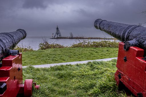 A close-up shot of two antique cannons pointing towards the Hoorn lighthouse