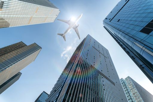 airplane fly over modern office buildings with sunshine, low angle view.
