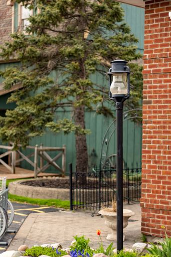 A vertical shot of a lamp on a street next to a brick wall