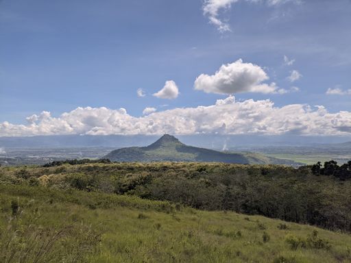 A beautiful green landscape with a hill and fluffy clouds in the background