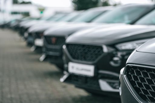 A selective focus shot of a lane of black and gray luxury cars parked on one lane