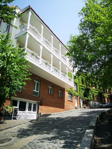 An exterior view of a historic brick building near trees in Tbilisi, Georgia