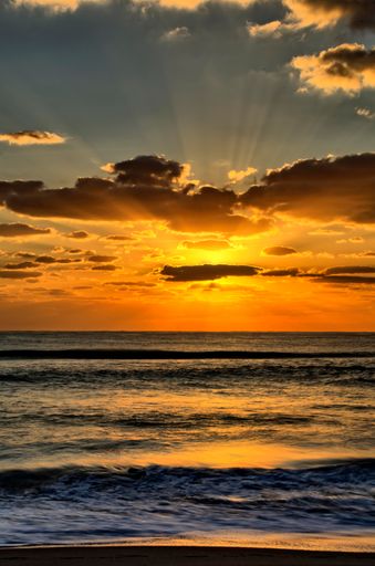 A vertical shot of a breathtaking sunset over the wavy sea