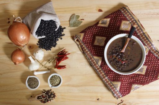 Herbs and Spices on Rustic Table With Black Beans in Background