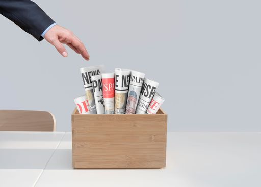 A man's hand taking newspapers in a wooden box on the table