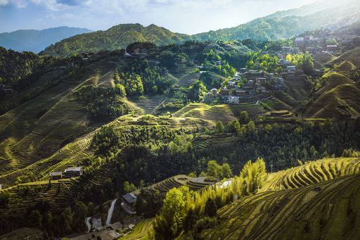 A beautiful shot of valley houses in the middle of green mountains area with fields, hills and cliffs