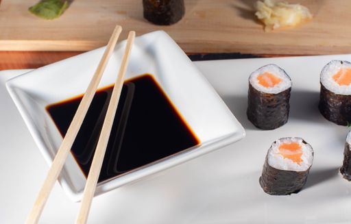 A close up shot of delicious sushi on a white plate served with soy sauce