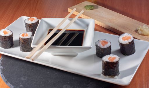 A close up shot of delicious sushi on a white plate served with soy sauce