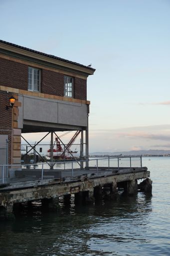 A vertical shot of a house on the water with a blue sky in the background