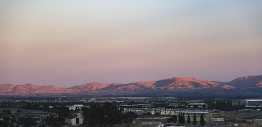 A wide shot of buildings with mountains in the distance under a blue and purple sky