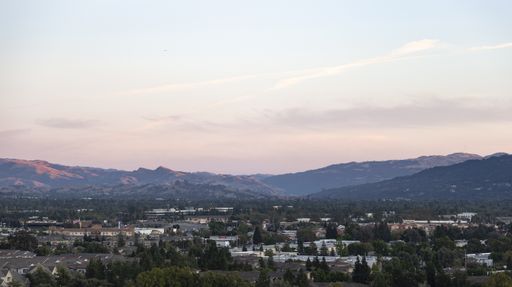 A beautiful shot of buildings with mountains in the distance under a cloudy sky