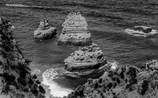 A beautiful view of rocks in the middle of the ocean, a grayscale shot