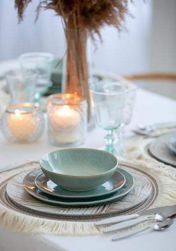 A vertical shot of ceramic dining set on the table with candles