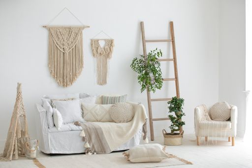 A grey sofa with wooden ladder plants and pillows in the room