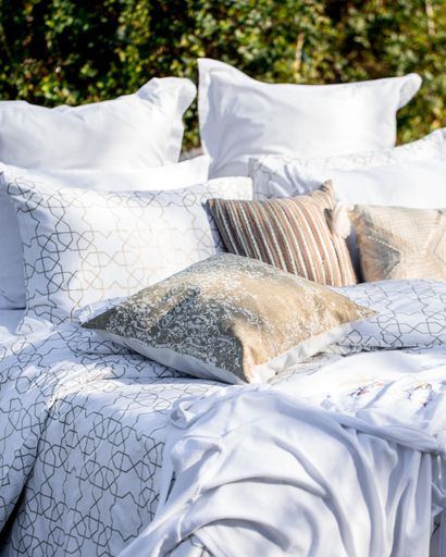 A bed with white patterned linen in the garden in the summer