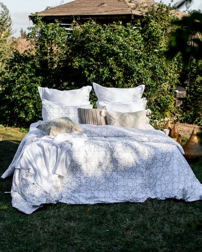 A bed with white patterned linen in the garden in the summer