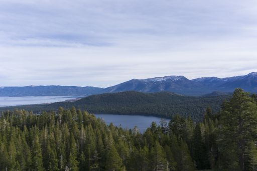 A high angle shot of pond in the middle of forested mountains under a cloudy sky