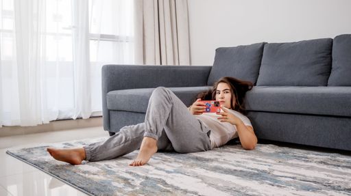 A caucasian girl lying on the floor of her house and taking pictures by her phone