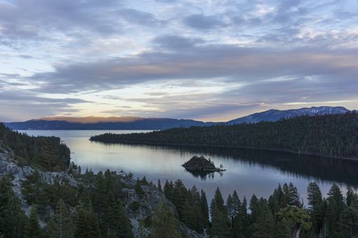 A high angle shot of the sea in the middle of forested mountains under a blue cloudy sky
