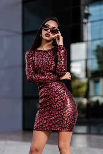 A young African-American woman in an elegant red dress posing in front of a modern office building