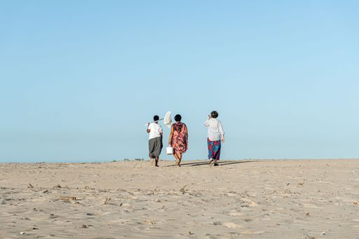 A group of people walking in the desert against blue sky