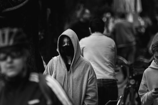 A grayscale shot of people in masks walking down the street in Munich, Germany, during the COVID pandemic.
