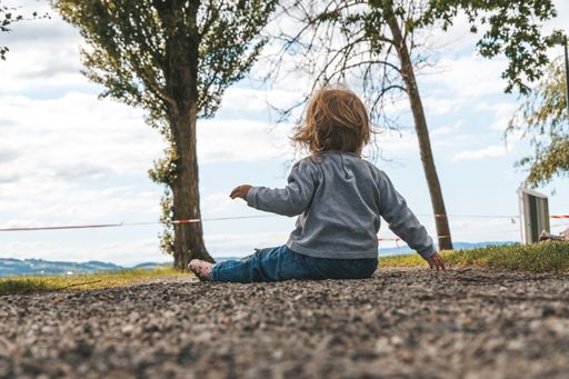 A closeup of a kid sitting on the ground at the park