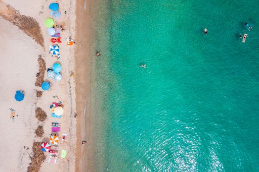 A beautiful aerial top view of colorful umbrellas on the beach on a sunny day