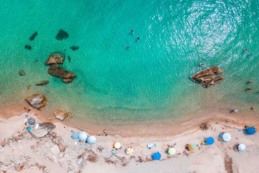 A beautiful aerial top-view of colorful umbrellas on the Greece beach coast on a sunny day