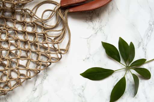 Eco flat lay with woven bag and plant on the marble tabletop
