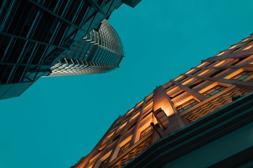 A low angle shot of modern towers with glass exterior under evening blue sky
