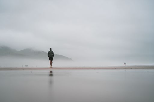 A breathtaking view of a man walking alone on the Canon beach on a foggy day