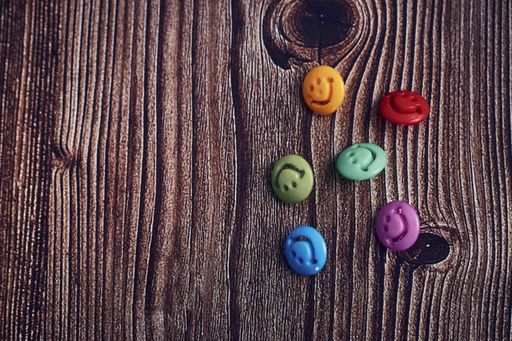 A closeup  shot of colorful buttons with smiley faces on a wooden table