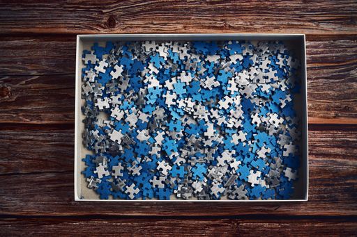 A closeup shot of small blue and grey puzzle pieces in the box