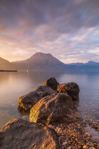 A vertical shot of Traunstein mountain near the body of water during sunset