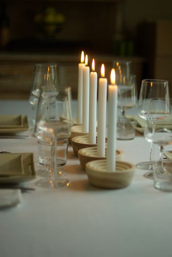 A vertical shot of a dinner table with wine glasses and candles with a blurred background