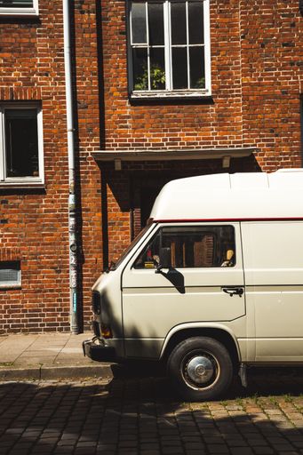 A vertical shot of the white van parked near the brown brick wall building. Hamburg, Germany.