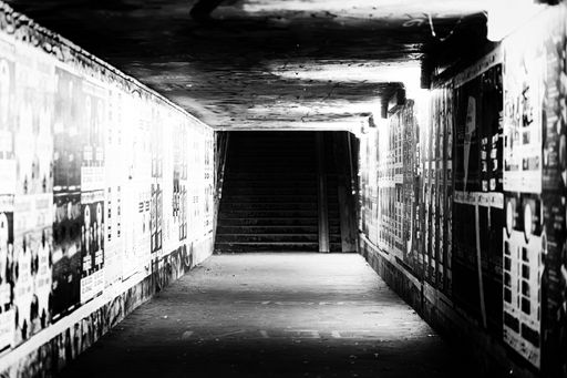 A grayscale shot of an underground passage with street art on the walls