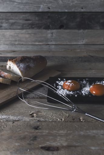 A vertical shot of a fresh sliced bread and egg yolks on a rustic wooden table
