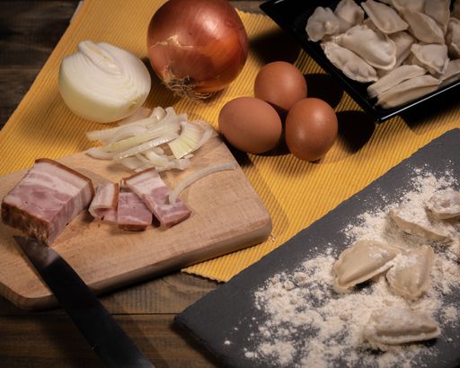 A high angle view of onions, eggs and meat on the table with raw dumplings on it