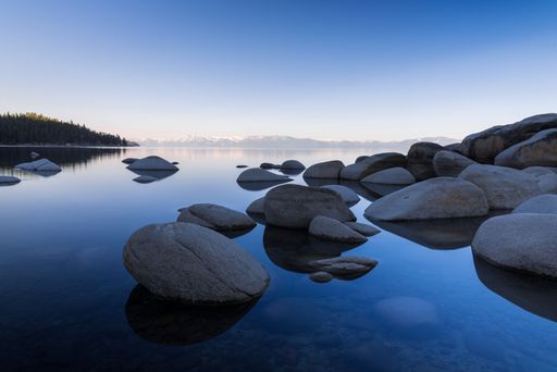 big rocks and clear lake with the reflection of the sky