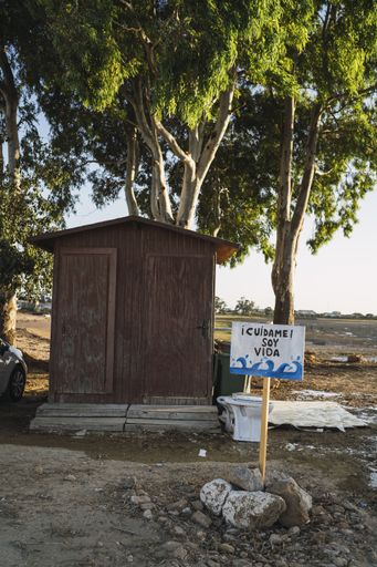 A vertical shot of a sign in spanish next to a dry lake translating to 'take care of me I am life'