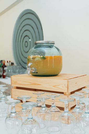 Vertical shot of a lemonade jar on a wooden crate with glass on the white table