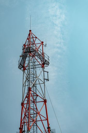 A vertical low angle shot of a Telecommunication tower under a a clear blue sky