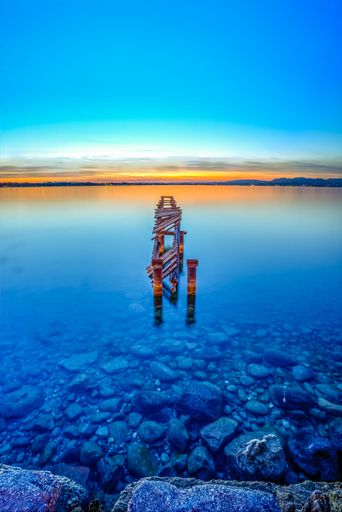 A vertical shot of wooden bridge in Garda lake in Italy during sunset